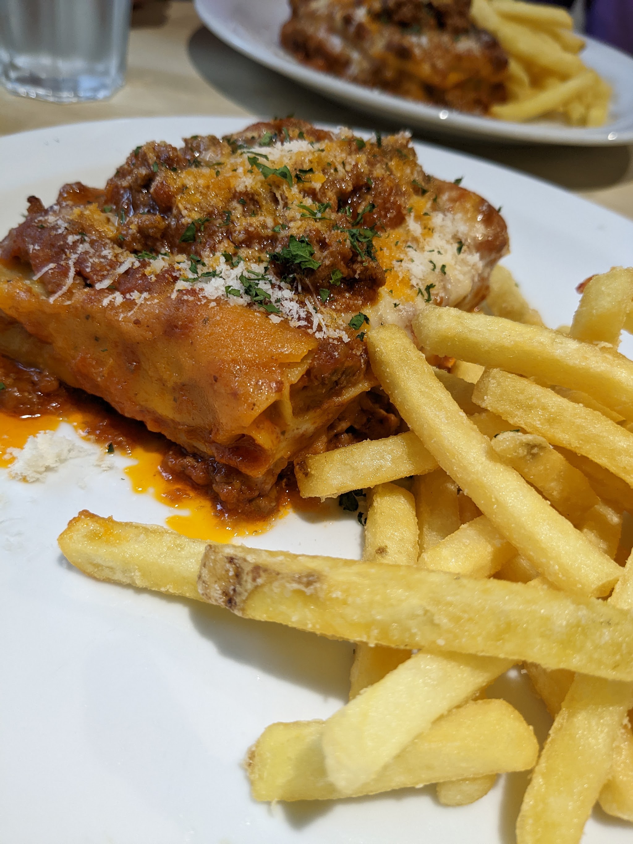 A plate of lasagne and chips photographed by a restaurant guest